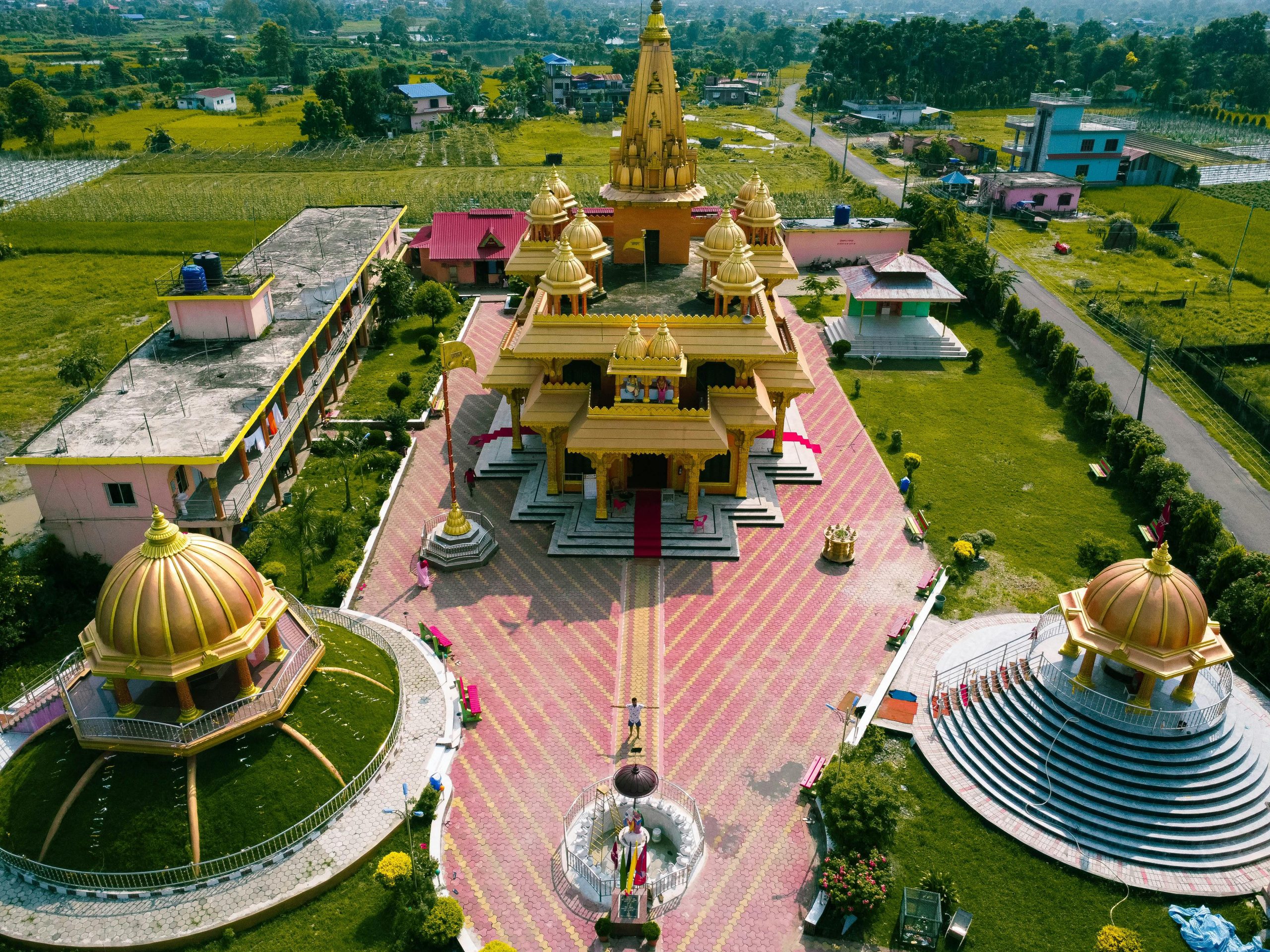 A stunning aerial shot of a golden Hindu temple surrounded by lush greenery, capturing its architectural beauty.